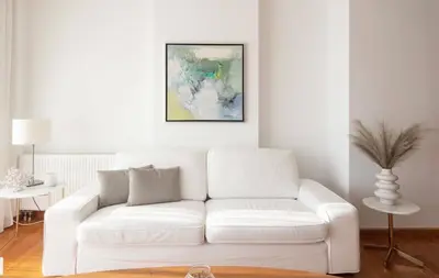 a white couch in a living room with a painting at ATHENS RIVIERA Grand Panoramic VILLAS I & II LAGONISSI in Kalívia Thorikoú