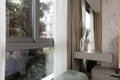 a living room with a window with a chair and a table at Nur Aparthotel Athens in Athens