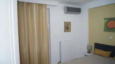 a bedroom with a bed and a window with a curtain at Electra in Saronida
