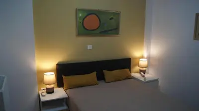 a bedroom with a bed with two lamps and a painting at Electra in Saronida