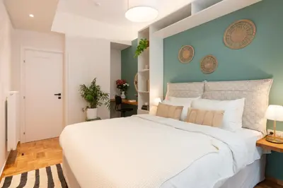 a bedroom with a large white bed with a blue wall at Adela's Apartment BR & LR Next to Metro and 20' From Acropolis in Athens