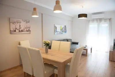 a dining room with a wooden table and white chairs at Newly renovated flat 500m from subway station (SKIATH_79) in Athens