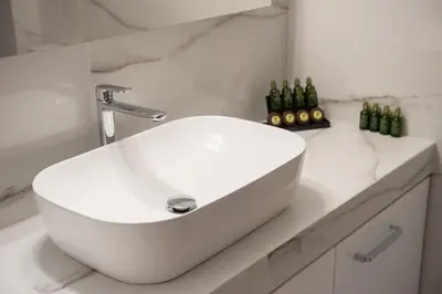 a white sink in a bathroom with bottles on a counter at Newly renovated flat 500m from subway station (SKIATH_79) in Athens