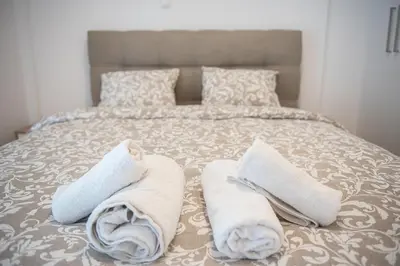a bed with towels and pillows on it at Bright apartment 8min to metro station (KOL_25) in Athens