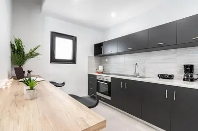a kitchen with a wooden table and black cabinets at Garden of Eden in Koukaki in Athens