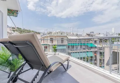 a chair on a balcony with a view of a city at Garden of Eden in Koukaki in Athens