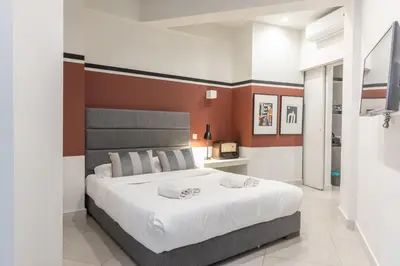 a bedroom with a large white bed with orange walls at Fantastic Central Athens Suite with shared Rooftop Deck in Athens