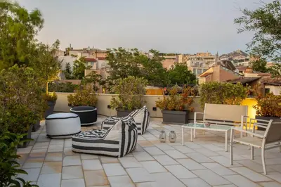 a patio with chairs and tables on a roof at Fantastic Central Athens Suite with shared Rooftop Deck in Athens