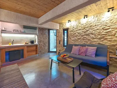 a living room with a blue couch and a stone wall at Sea View Garden Suites in Piraeus