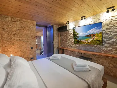 a bedroom with a bed and a tv on a stone wall at Sea View Garden Suites in Piraeus