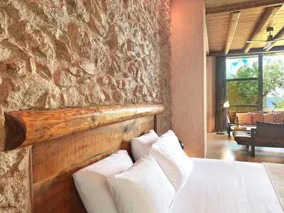 a bedroom with a stone wall and a bed with pillows at Sea View Garden Suites in Piraeus
