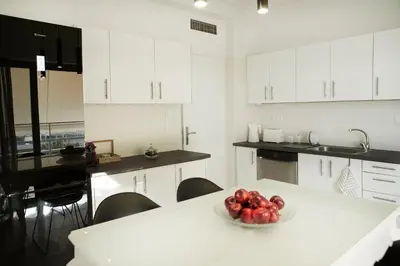 a white kitchen with a bowl of fruit on a table at Luxury Apartment with Exceptional View in Athens