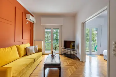a living room with a yellow couch and a tv at Spacious High-Ceiling 2-Bedroom by Acropolis Museum in Athens