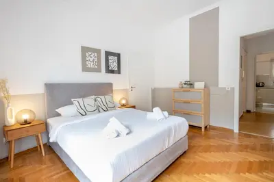 a bedroom with a white bed and a wooden floor at Spacious High-Ceiling 2-Bedroom by Acropolis Museum in Athens