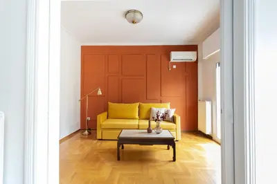 a living room with a yellow couch and a table at Spacious High-Ceiling 2-Bedroom by Acropolis Museum in Athens