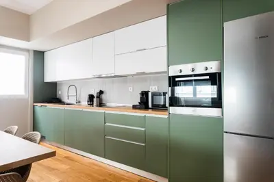 a kitchen with green and white cabinets and a table at The Gate by Zoia Living in Athens