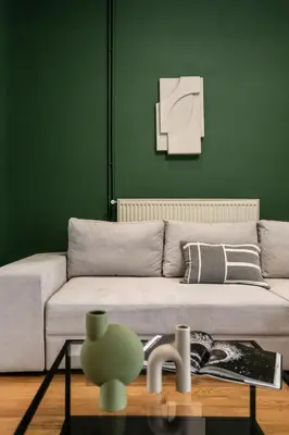 a living room with a couch and a green wall at The Gate by Zoia Living in Athens