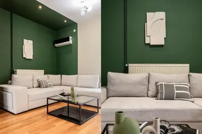 a living room with a white couch and a green wall at The Gate by Zoia Living in Athens