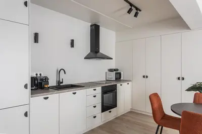 a kitchen with white cabinets and a table at Kookaki by Zoia Living in Athens