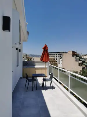 a table and chairs on a balcony with an umbrella at Ikarus in Athens