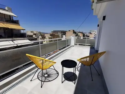 a balcony with two chairs and a view of a city at Ikarus in Athens