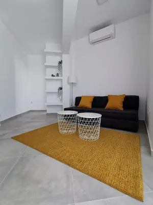 a living room with a black couch and a yellow rug at Ikarus in Athens