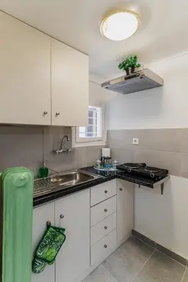 a kitchen with white cabinets and a sink at Green boho apartment in Athens