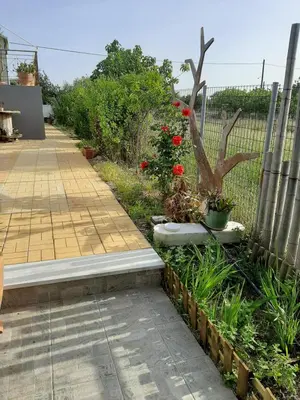 a garden with a fence and a sidewalk at Helen's cozy studio (close to the airport) in Koropíon