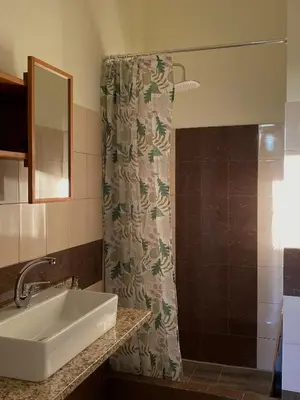 a bathroom with a sink and a shower curtain at Helen's cozy studio (close to the airport) in Koropíon