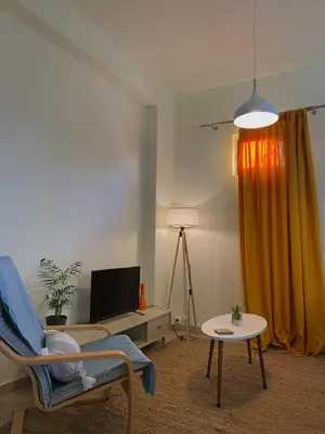 a living room with a chair a table and a television at Helen's cozy studio (close to the airport) in Koropíon