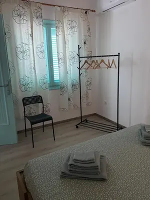 a bedroom with a bed and a chair and a window at Spata Lykourgos Homes in Spáta