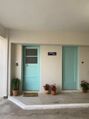 a building with two blue doors and potted plants at Spata Lykourgos Homes in Spáta