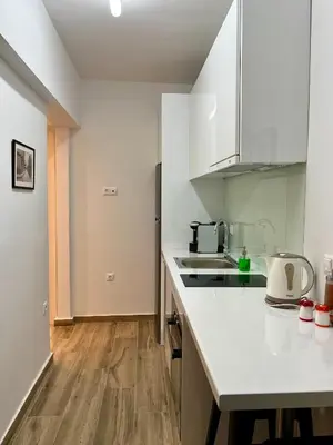 a kitchen with white countertops and a wooden floor at Mr Negri in Athens