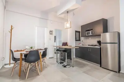 a kitchen with a table and a stainless steel refrigerator at Garden of Eden in Neos Kosmos in Athens