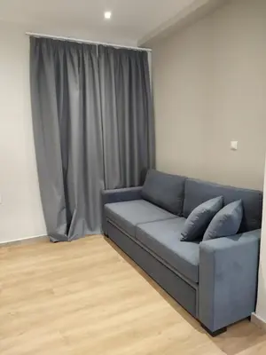 a living room with a blue couch in front of a window at New Amaryllis Hotel in Athens