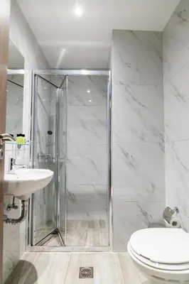 a bathroom with a shower and a toilet and a sink at New Amaryllis Hotel in Athens