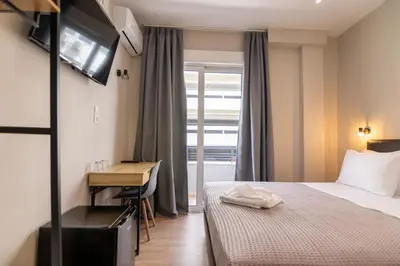 a hotel room with a bed and a desk and a window at New Amaryllis Hotel in Athens