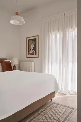 a white bedroom with a bed and a large window at Sunny and Comfy Apartment in kolonaki in Athens