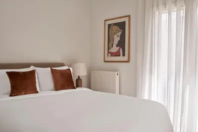 a white bedroom with a white bed and a window at Sunny and Comfy Apartment in kolonaki in Athens