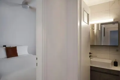 a white bathroom with a sink and a mirror at Bright Apt-Archeological Museum in Athens