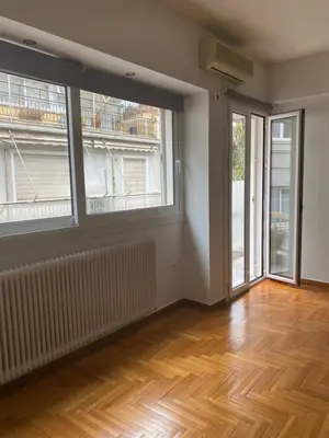 an empty room with two large windows and a wooden floor at Apartment in Fancy Athenian Neighbourhood in Athens