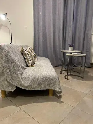 a couch with a blanket and a side table at Cozy Apartment In The Heart Of Athens in Athens