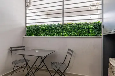a table and chairs next to a green hedge at Elvita Apartments 4 in Athens