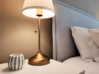 a gold lamp on a table next to a bed at Vouliagmeni Iasonos Residence Central Stylish Flat in Athens