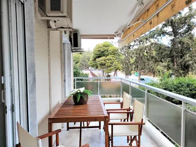 a balcony with a wooden table and chairs at Vouliagmeni Iasonos Residence Central Stylish Flat in Athens