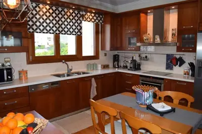 a kitchen with wooden cabinets and a table with oranges on it at Grand Villa Lagonisi in Kalívia Thorikoú