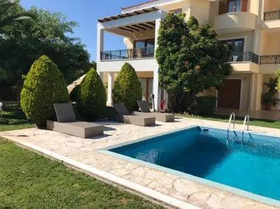 a villa with a swimming pool in front of a house at Grand Villa Lagonisi in Kalívia Thorikoú