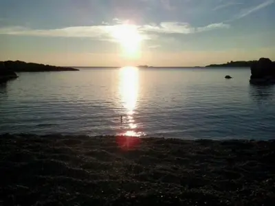a sun setting over a large body of water at Grand Villa Lagonisi in Kalívia Thorikoú