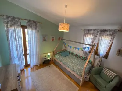 a bedroom with a bed and a chair and windows at Grand Villa Lagonisi in Kalívia Thorikoú