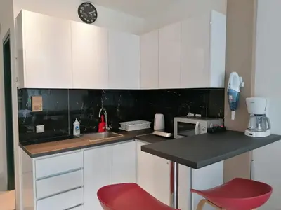 a kitchen with white cabinets and a red chair at Syntagma Nest Apartment in Athens